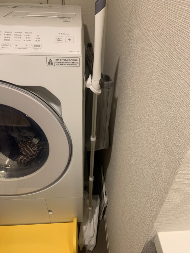 洗濯機の右側。すぐに掃除出来るようにフローリングワイパーを取り付けていて、奥には洗濯カゴをマグネットのクリップに挟んで掛けています。