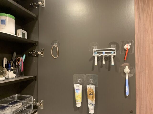 洗面台鏡裏の扉。歯ブラシ・歯磨き粉・ヘアゴムを吊り下げて収納しています。